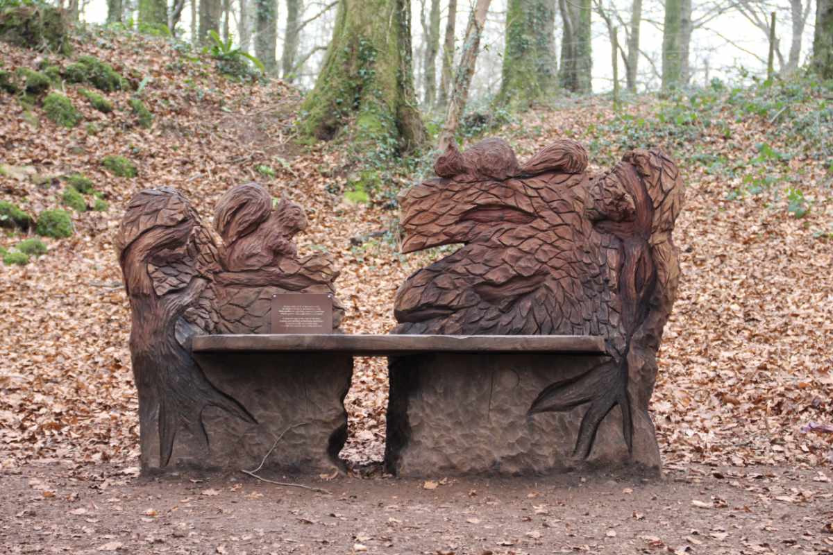 Wooden sculpture of a bench with squirrels around it