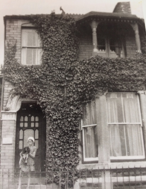 Photo of house with girl holding a dog, taken in 1928