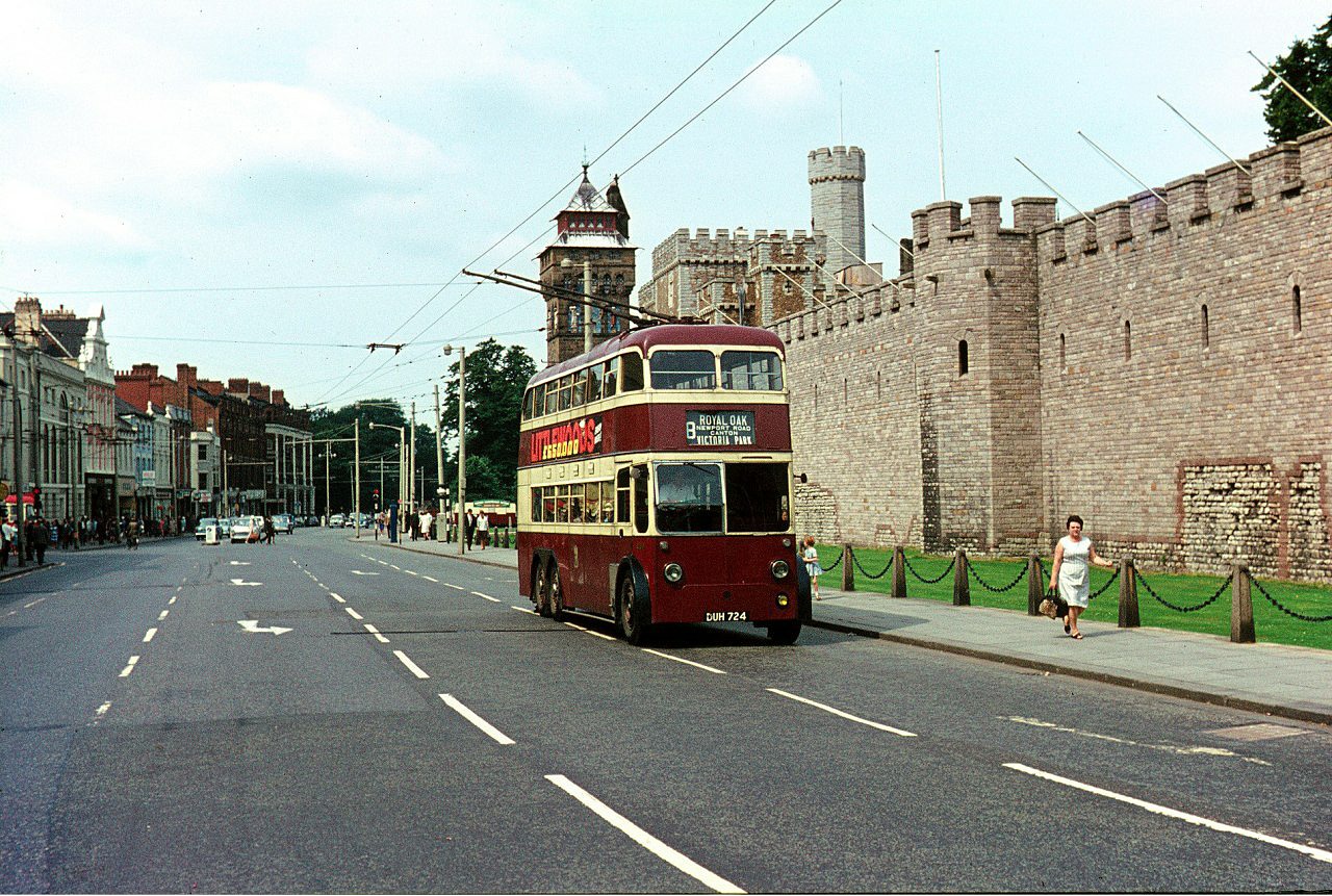 A trolleybus on a city street with a castle in the background.